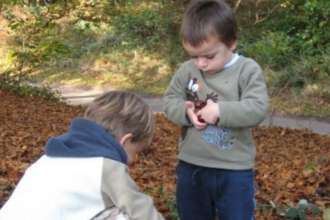 Two children play in the Autumn leaves