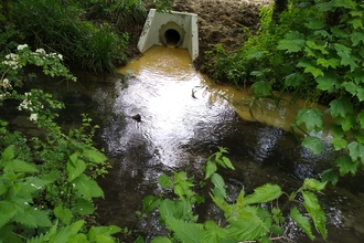 A photo of a pipe in a riverbank discharging waste into a river