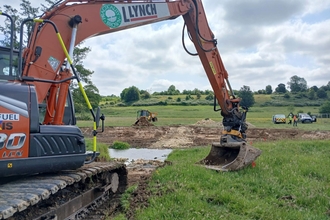 A big orange digger on the banks of the River Ash